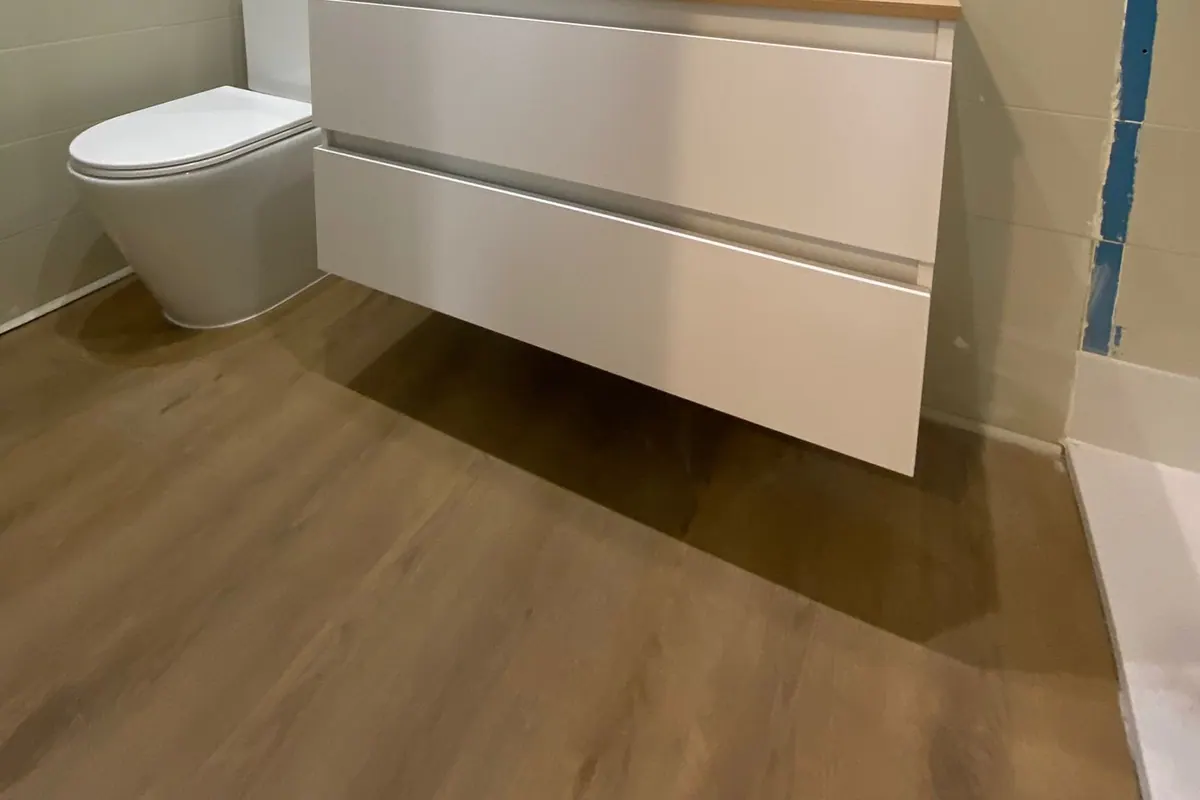 Baño con mueble de lavabo e inodoro instalado